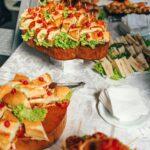 Close-up of a vibrant sandwich buffet with fresh lettuce and garnish on a tablecloth.
