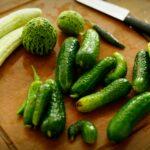 Maladies des concombres en serre et en plein air avec photos et traitements A variety of fresh cucumbers arranged on a wooden chopping board with a knife.