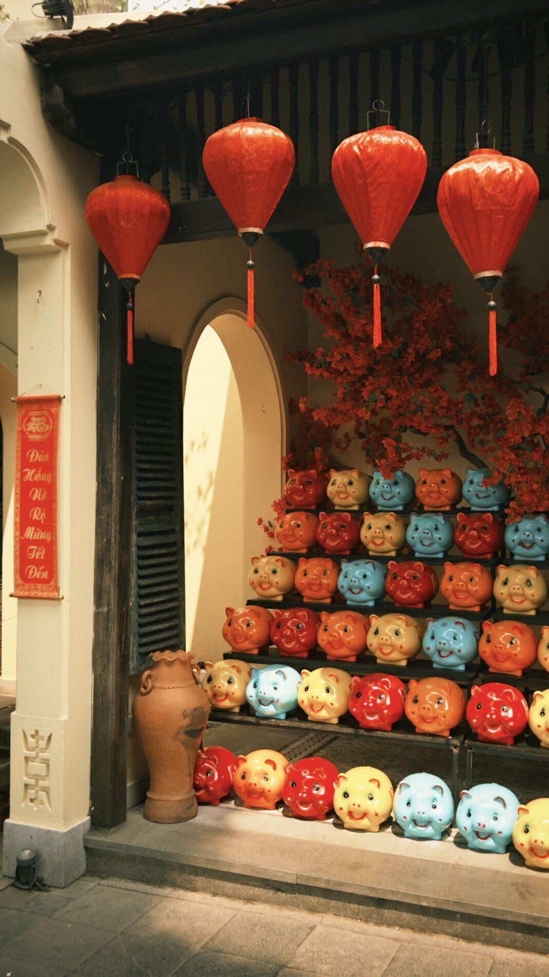 Vibrant display of red lanterns and pig figurines in an outdoor shop setting.