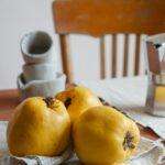 Close-up of fresh yellow quince fruit on a rustic table setting indoors.