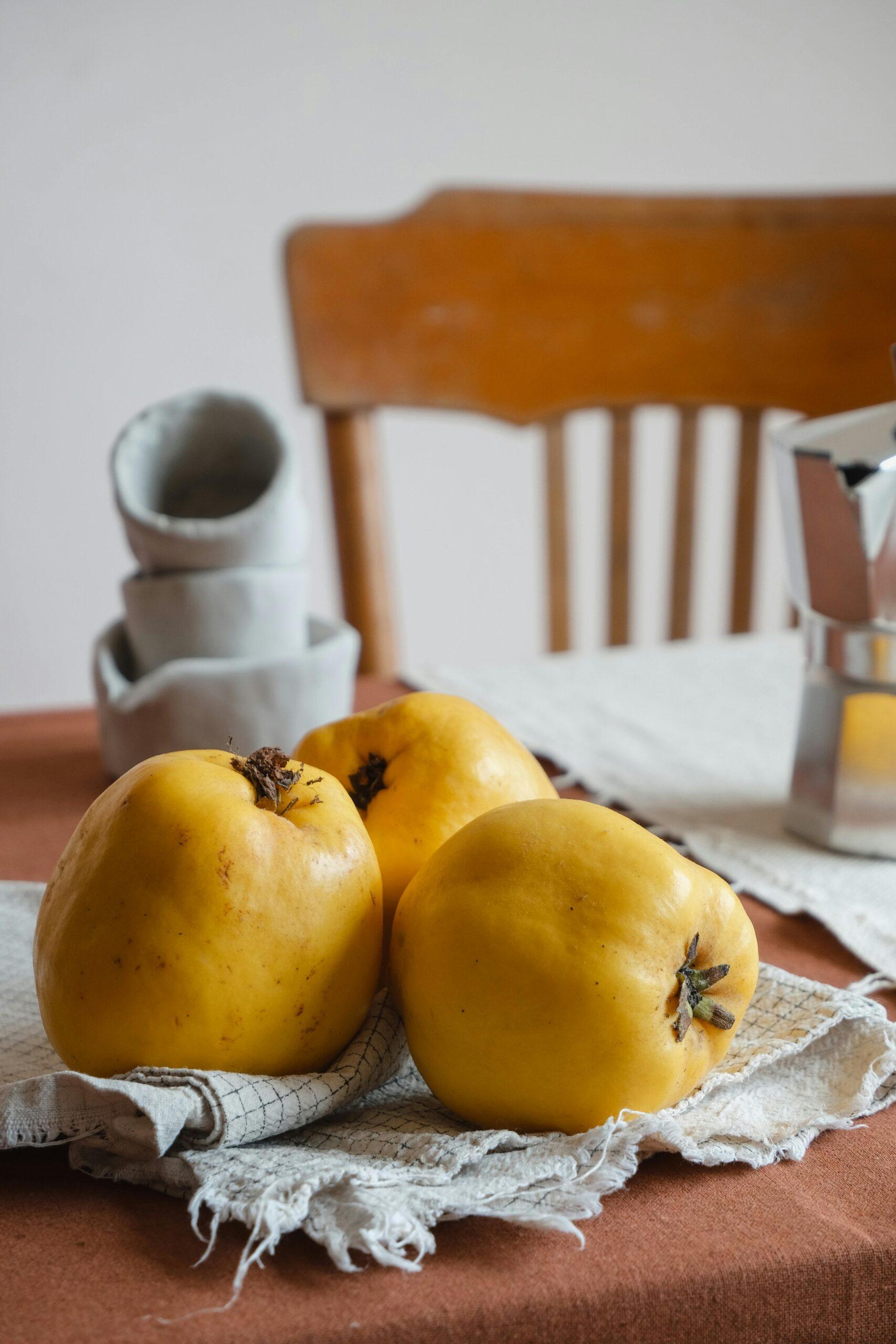 Close-up of fresh yellow quince fruit on a rustic table setting indoors.