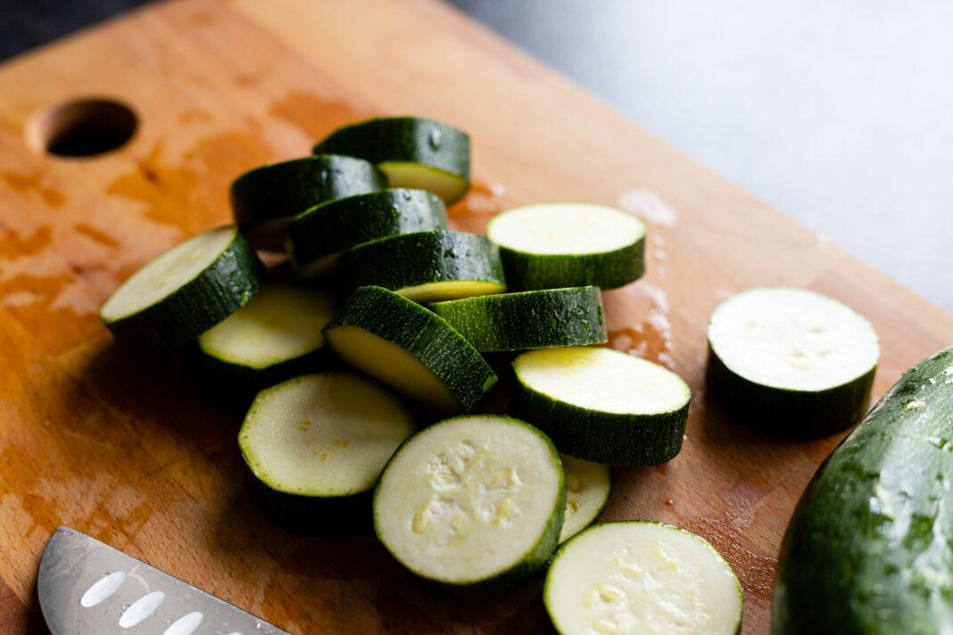 Close-up of sliced zucchini on a wooden cutting board for food preparation.