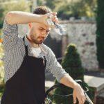 Lunes rouge et rousse : le grand quiproquo qui embrouille les jardiniers A tired gardener wipes sweat, resting from lawn care in a sunny backyard.