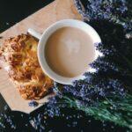 Bouturer la lavande : les deux saisons qui marchent à tous les coups A cup of coffee and pastry on a wooden board surrounded by lavender flowers.