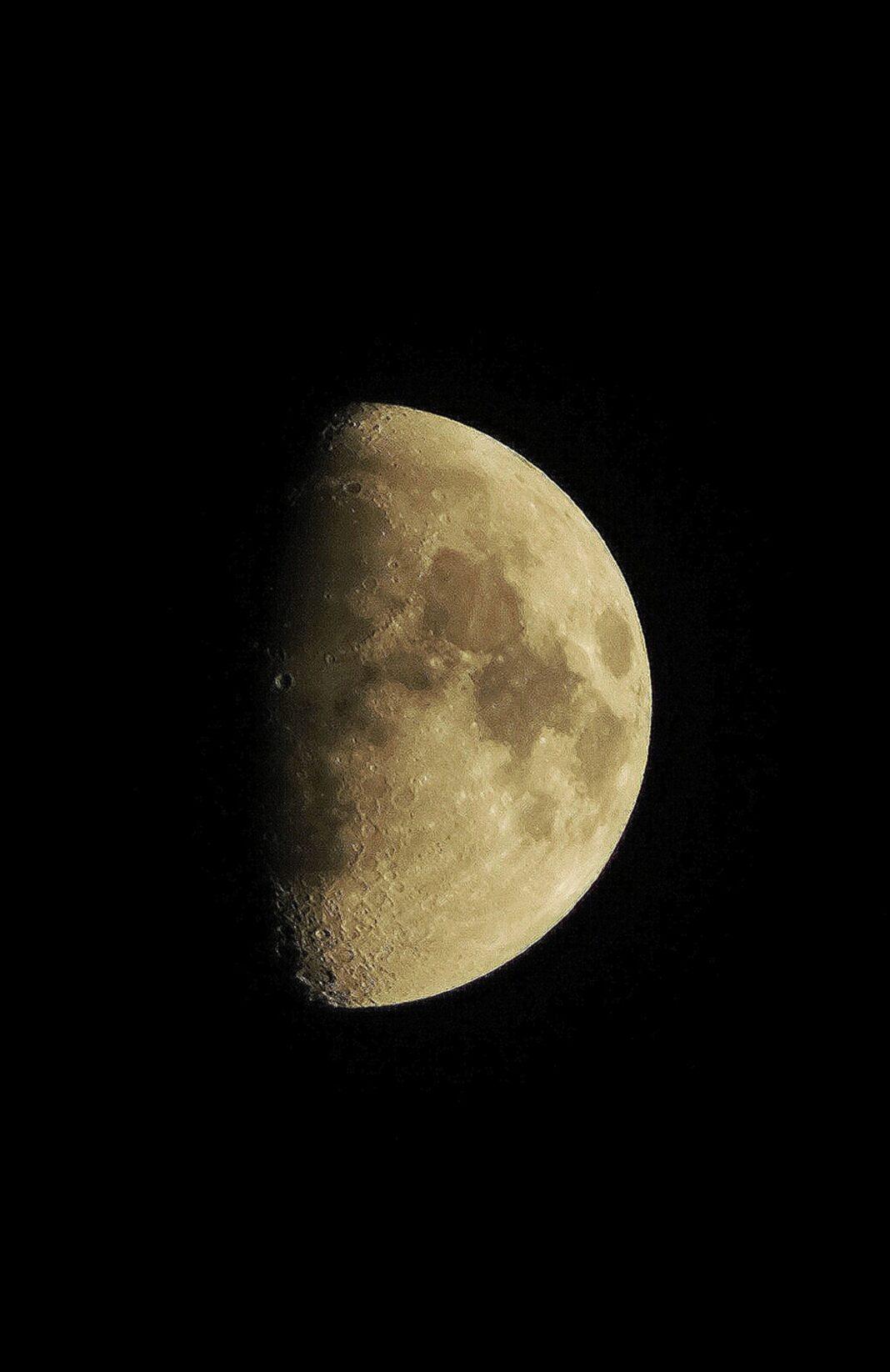 Detailed close-up of a quarter moon against a dark night sky.