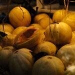 Faire mûrir le melon : 7 astuces imparables pour des melons parfaits Yellow melons displayed in a market setting, showcasing fresh produce.