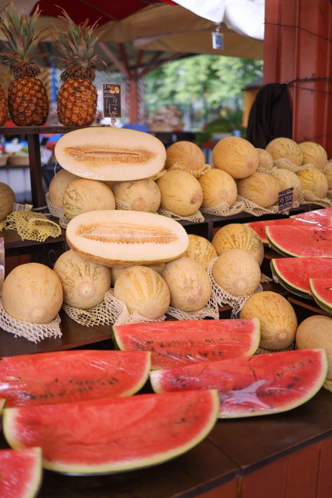 A vibrant market stall showcasing fresh watermelons, melons, and pineapples.