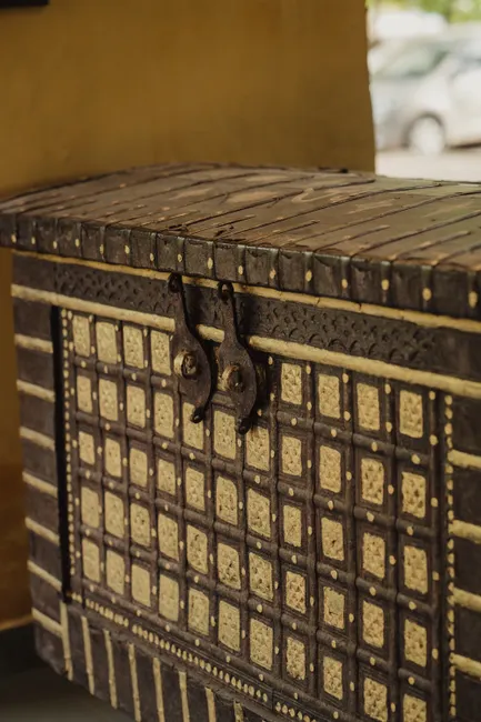 A detailed close-up of a traditional wooden storage chest with intricate carvings in Amblash, India.