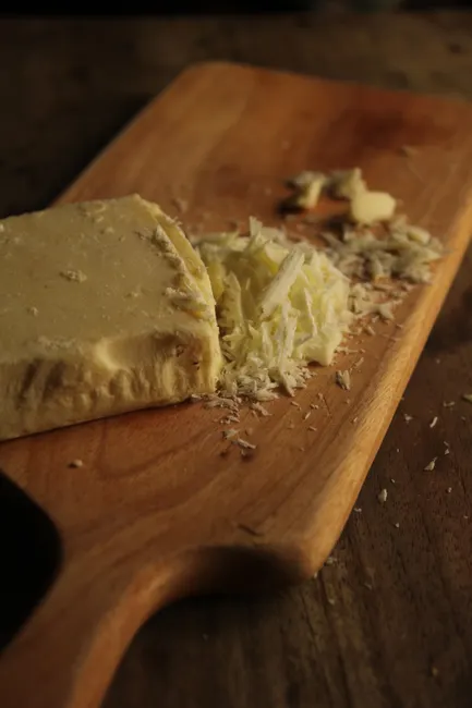 Close-up of freshly grated horseradish on a wooden cutting board, perfect for culinary use.