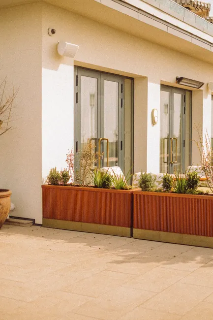 Contemporary terrace with glass doors and planters in an urban setting, showcasing modern architecture.