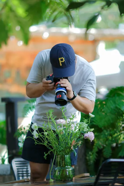 Man photographing flowers in a garden with focus on vibrant blooms.