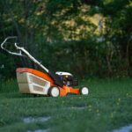Tondeuse manuelle: 200 à 500 m2, mollets en renfort A lawn mower sits on a green lawn in a backyard, ready for yard work.