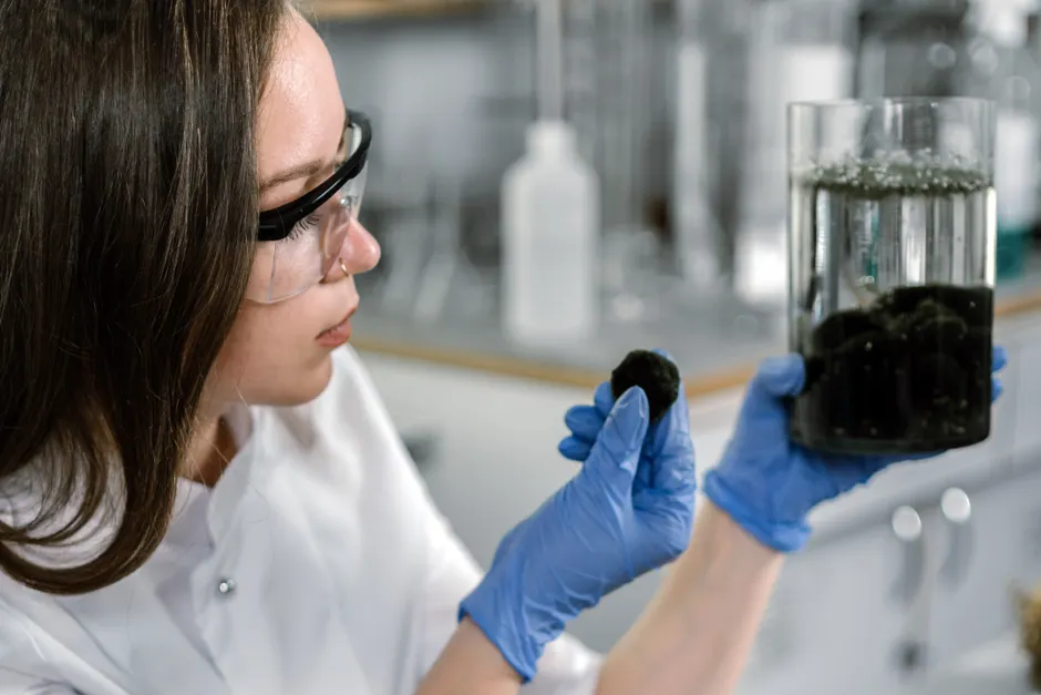 A scientist in a lab coat examines a sample with laboratory equipment.