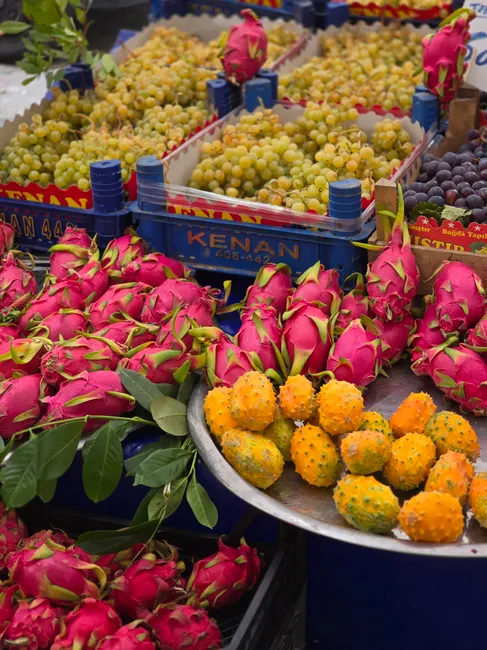 Colorful fruit market showcasing dragon fruit, grapes, and kiwano melon.