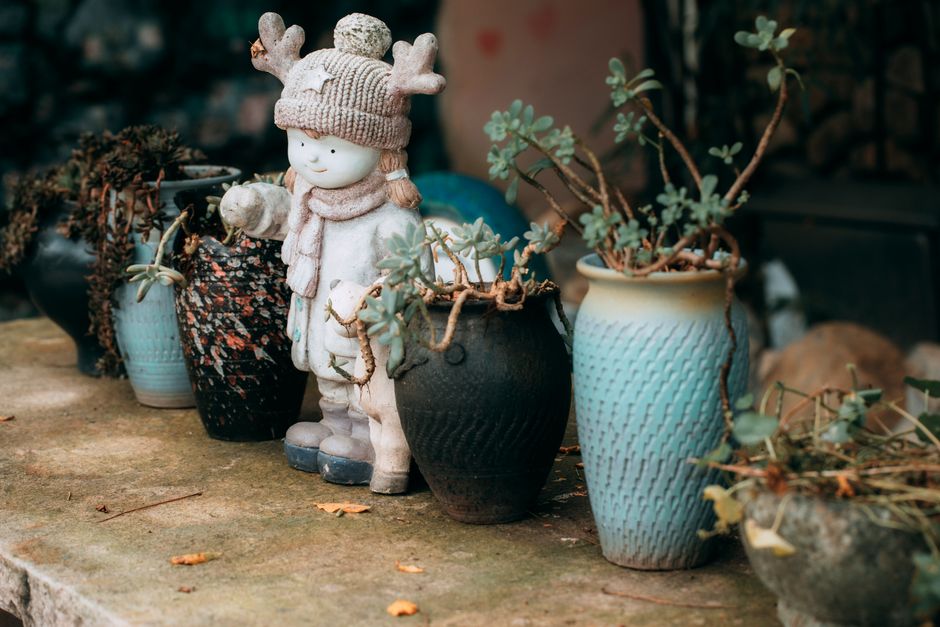 Cute winter-themed statue with potted plants on a rustic stone surface.