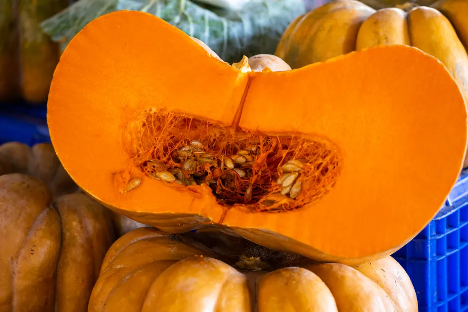 Detailed view of a fresh pumpkin cut in half showing seeds and flesh, perfect for autumn themes.