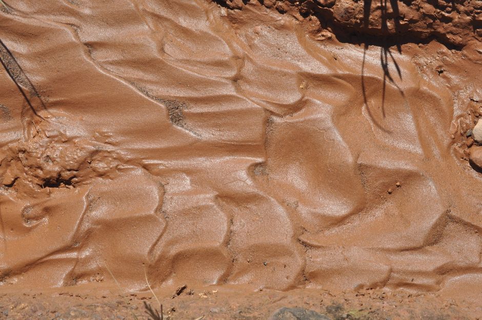 Detailed view of wet clay soil with a rippled surface, showcasing natural patterns and textures.