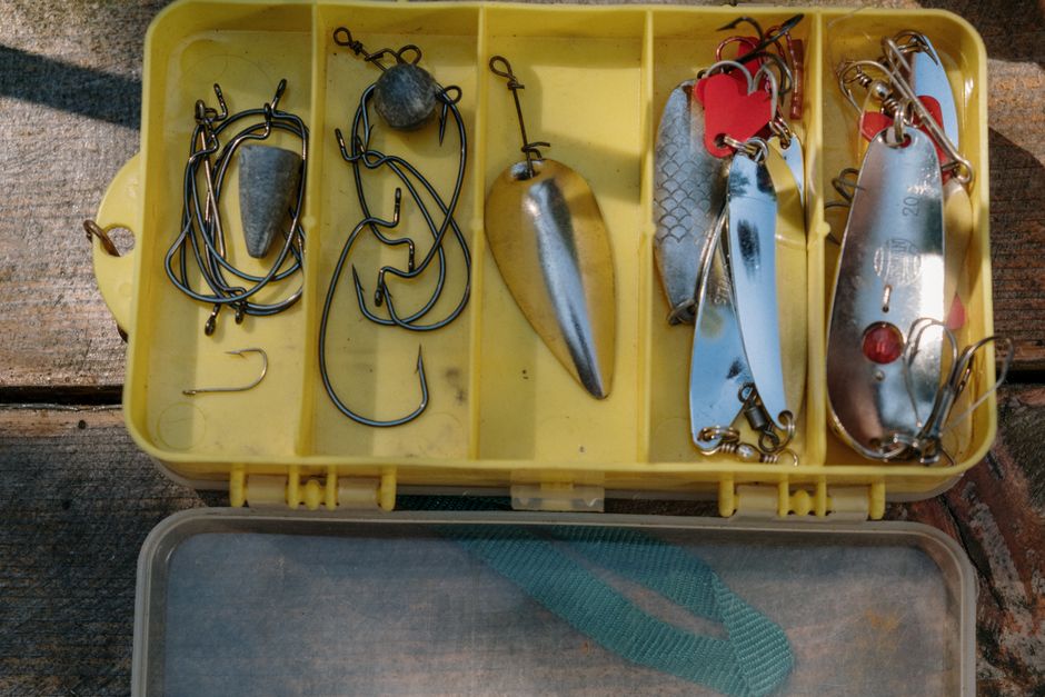 Yellow tackle box containing various fishing hooks and lures for angling enthusiasts.