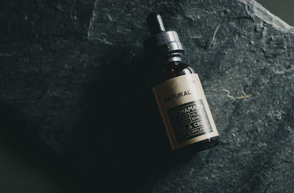 A CBD tincture bottle displayed on a textured dark stone background emphasizing natural wellness.
