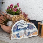 Plantes en pot : 8 °C, le signal d'alarme avant l'hiver A cozy outdoor corner with potted plants and a decorative winter scene on stone, alongside a rustic lantern.