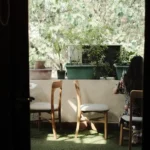 Jardin d’hiver en véranda : 15 à 20 m², pas un empilement de pots A serene balcony view featuring a woman sitting amidst potted plants and chairs.