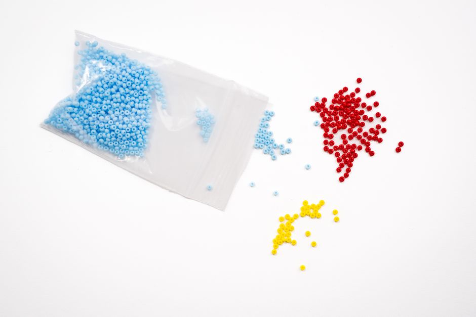 Brightly colored red, yellow, and blue beads scattered on a white backdrop, ideal for crafting and jewelry making.