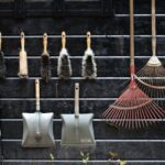 Neatly arranged garden tools hanging on a rustic wooden wall.