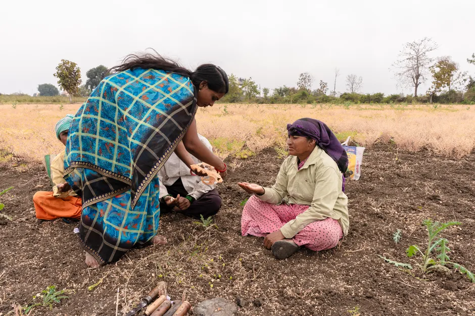 Two Indian women farmers planting seeds in a rural field in Nagpur, showcasing traditional agriculture practices.